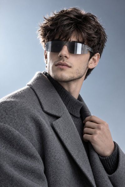 Male model in ash-gray coat poses against icy gradient backdrop
