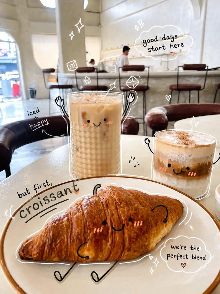A smiling iced coffee and pastry sit on a cozy café table