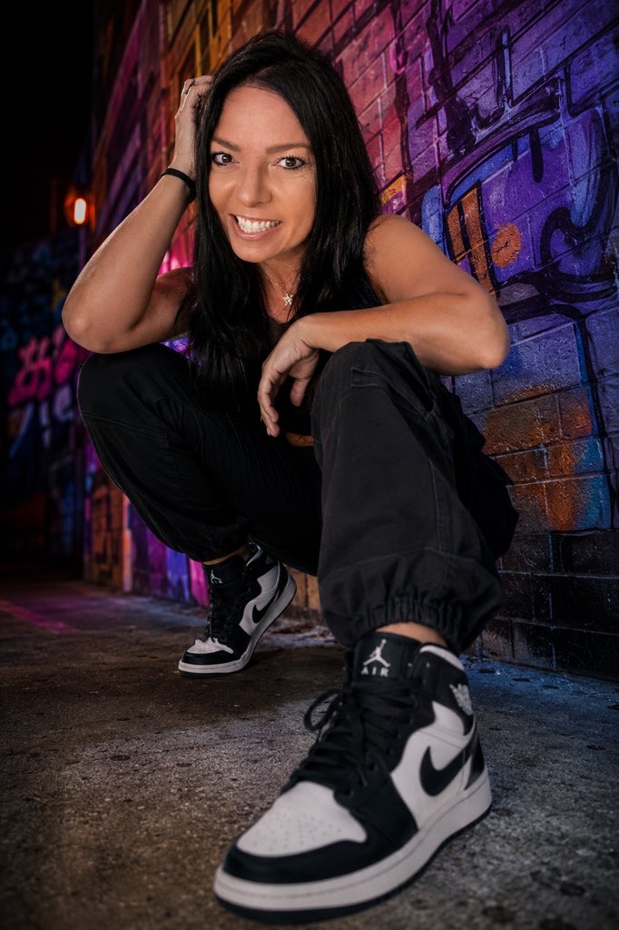 Model crouches in graffiti alley wearing luxury streetwear