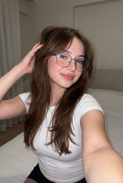 A young woman takes a playful selfie on a cozy bed