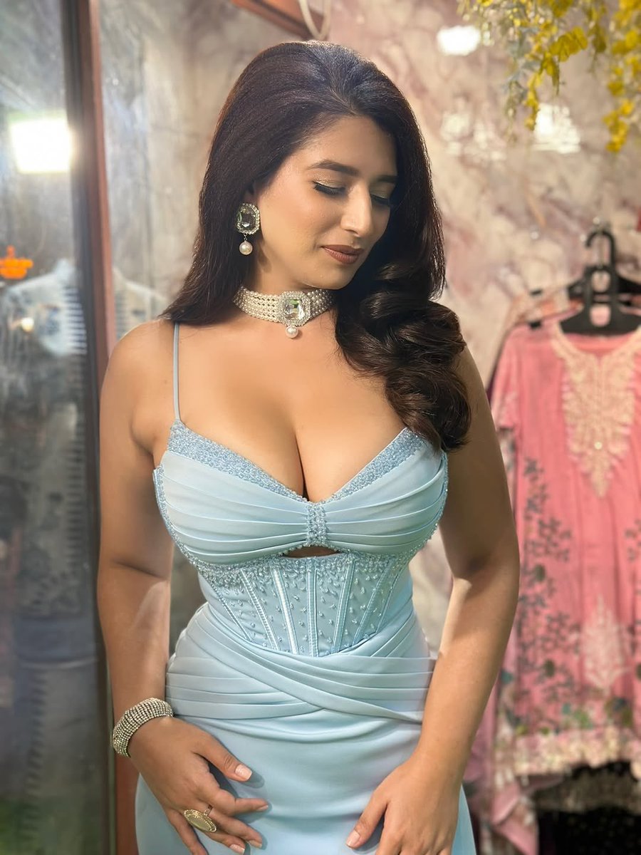 Elegant woman in icy blue gown poses in luxury boutique