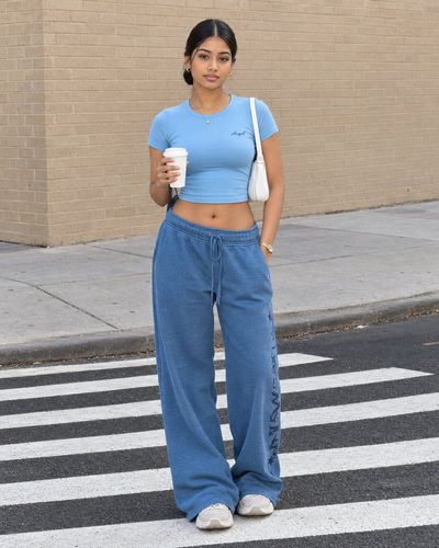 Confident woman in streetwear stands on zebra crossing in daylight
