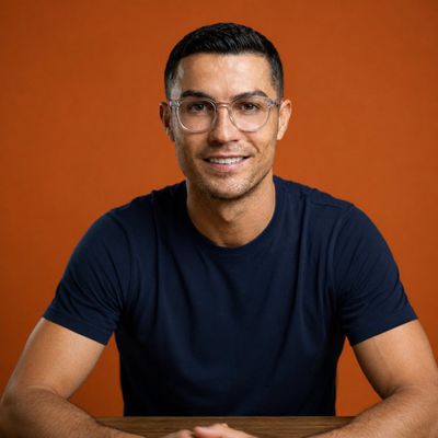 Young man with transparent glasses smiles confidently in orange studio portrait