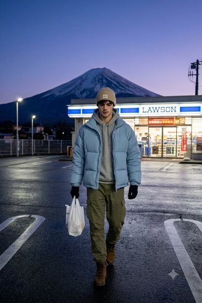 Man walks across a wet parking lot with Mount Fuji behind