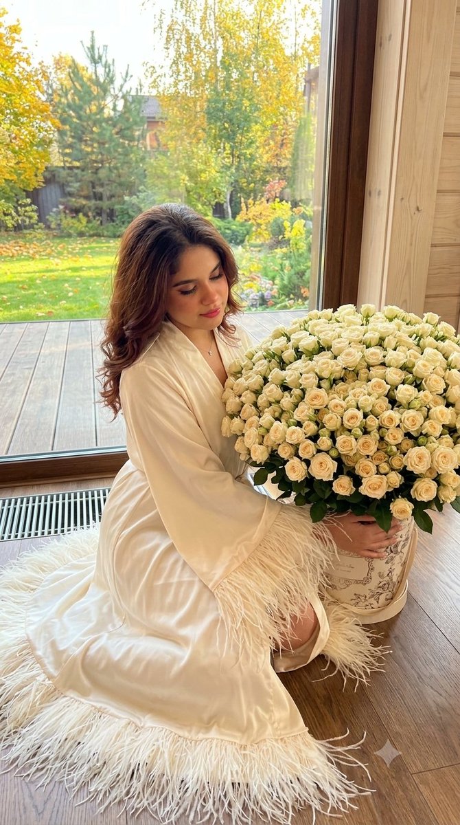 Woman in Silk Robe Sits on Wooden Floor with Cream Roses