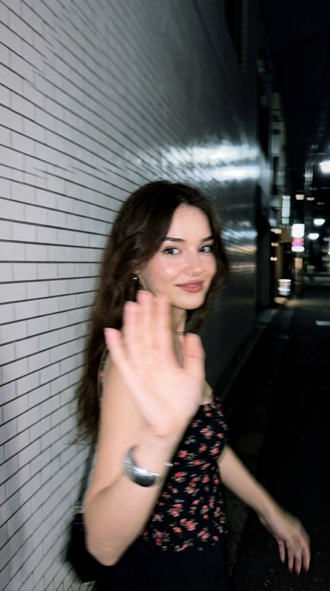 A surprised woman turns back while blocking a smartphone flash at night.