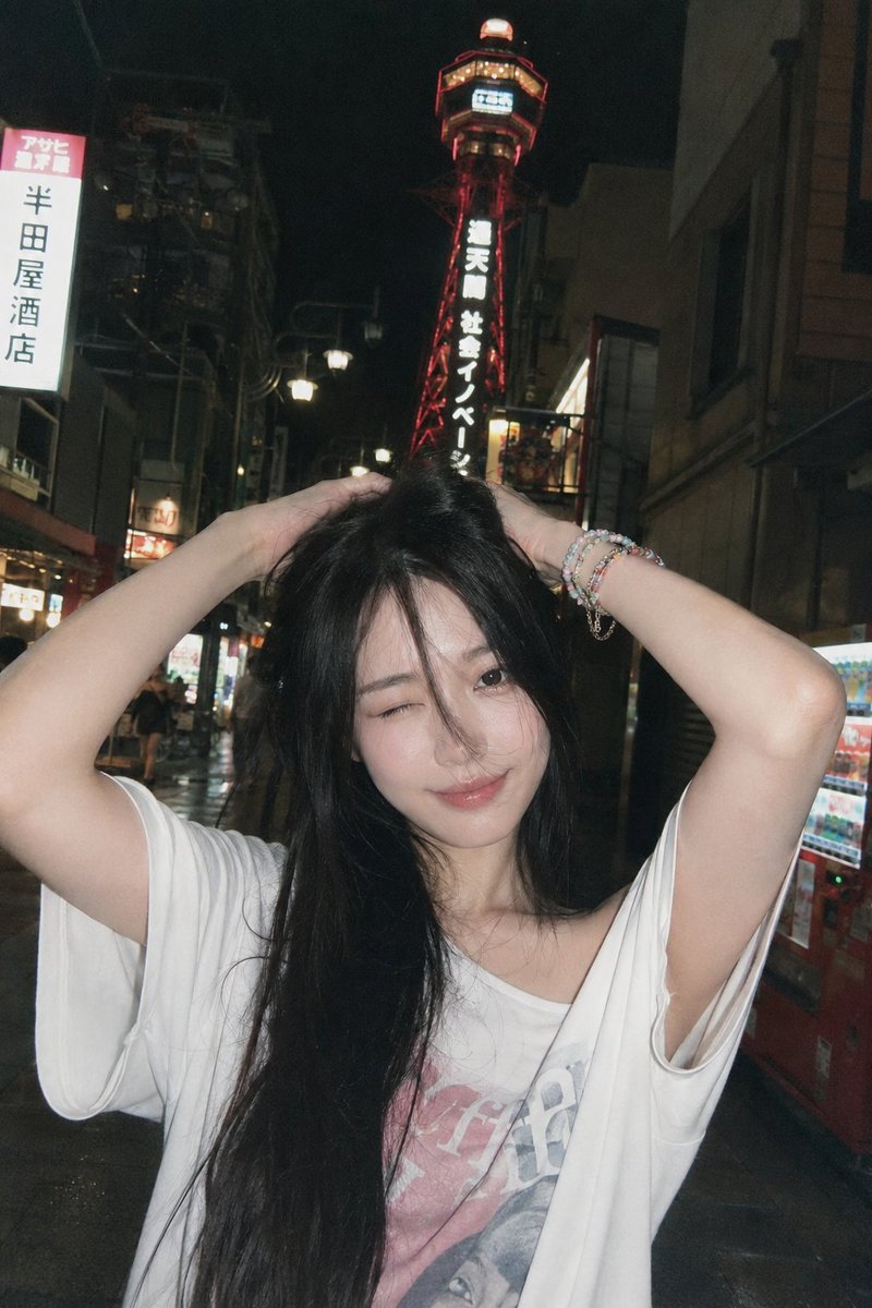 A young woman winks playfully under neon lights in Osaka at night