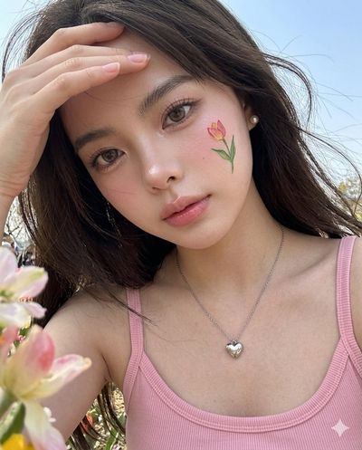 A woman with tulip face art tilts her head in a spring selfie