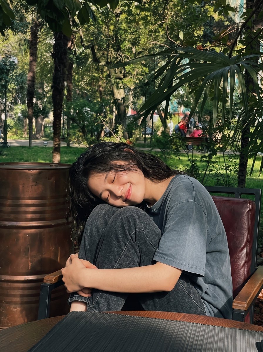 Sunlit East Asian Woman Smiling on a Park Bench