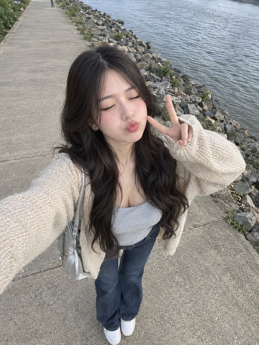Young woman poses with peace sign by the river in daylight