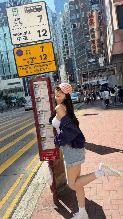 Young woman smiles beside Hong Kong bus stop in afternoon sun