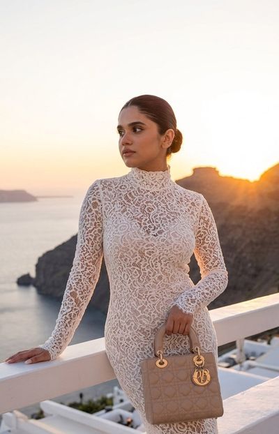 A woman in a white dress poses on a terrace at sunset