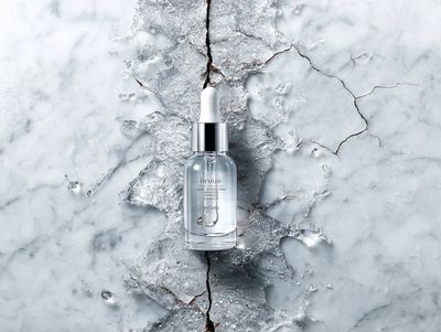 Beauty Product Hovering Above Ingredient Cross-Section on Marble