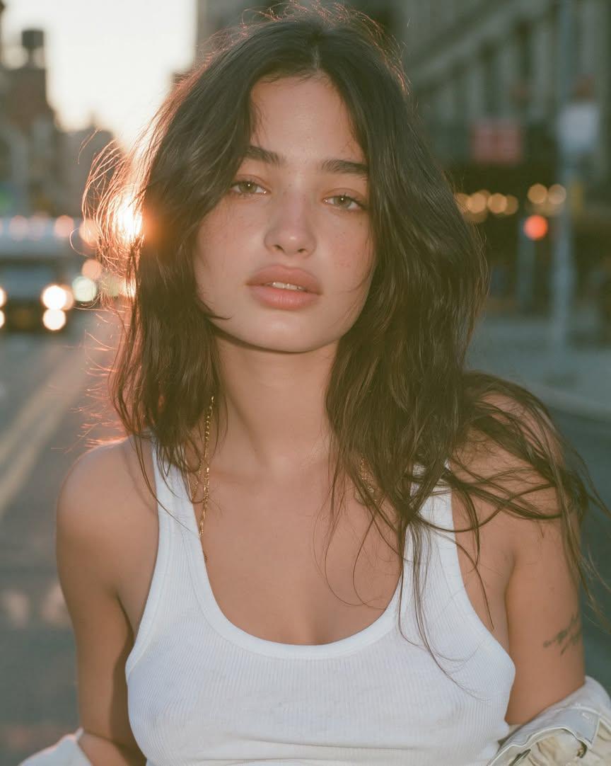 Young woman stands on a quiet street in warm golden hour light