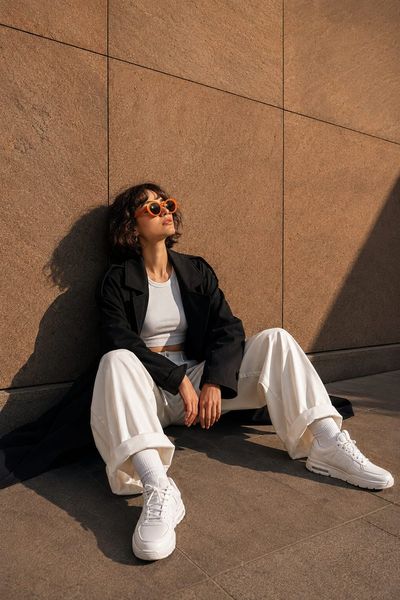 A woman in sunglasses sits against a textured stone wall