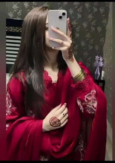 A woman in red dress captures mirror selfie with henna-decorated hands