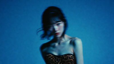 Woman in leopard corset poses against blue seamless backdrop