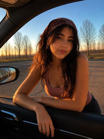 Woman leaning from car glows in warm sunset light