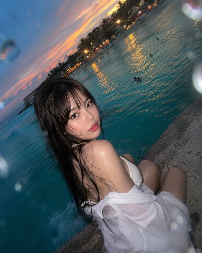 Wet-haired woman glances back on a concrete pier at sunset