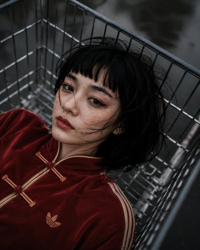 A woman lounges in a shopping trolley under cloudy skies