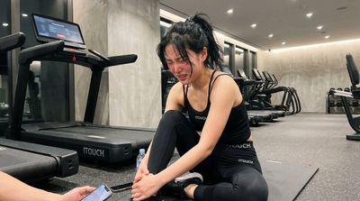 A young woman sits on the gym floor after a treadmill fall