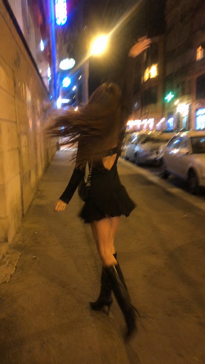 A woman spins under warm streetlights on a busy night