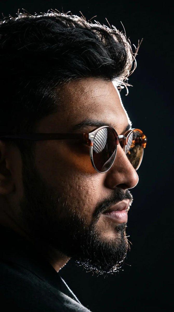 Young man's profile emerges from darkness with rim-lit sunglasses