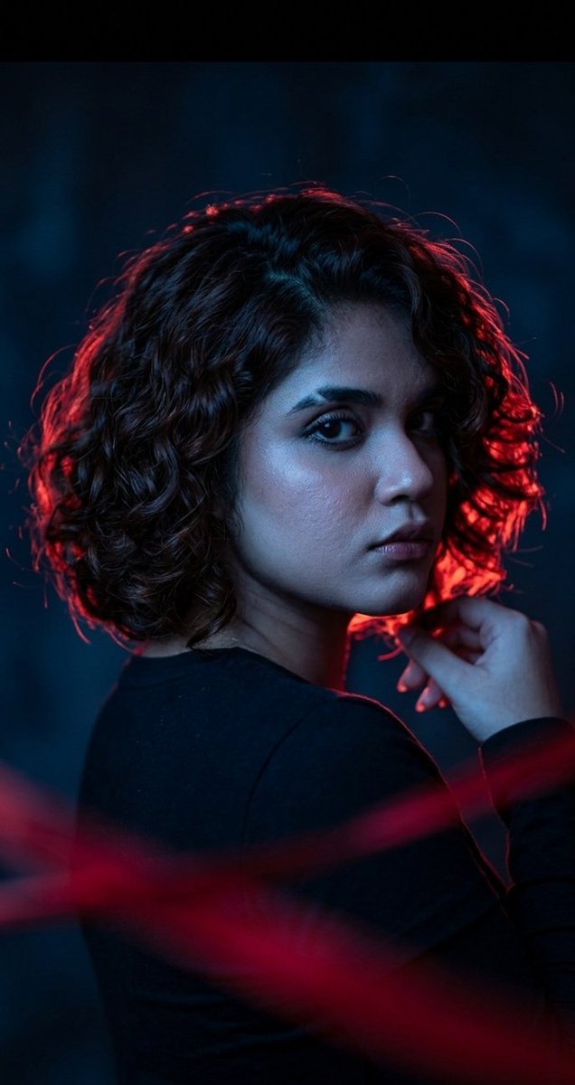 Dr. Samia gazes back through red and blue cinematic light