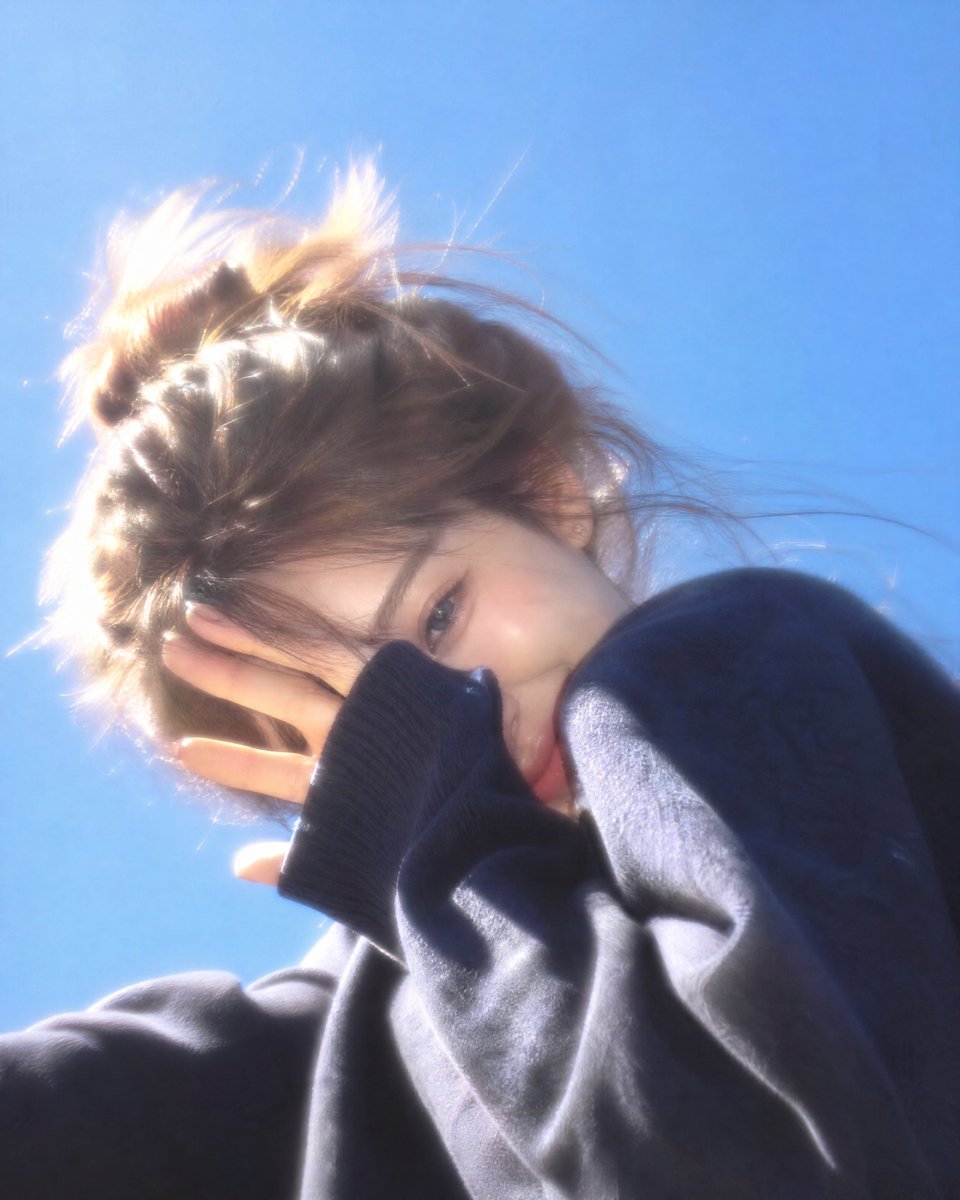 Woman shields face laughing under bright cobalt sky
