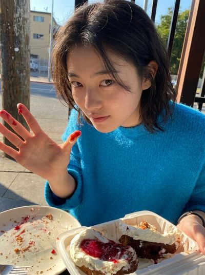 Woman Shows Jam-Stained Fingers While Leaning Over Cafe Table