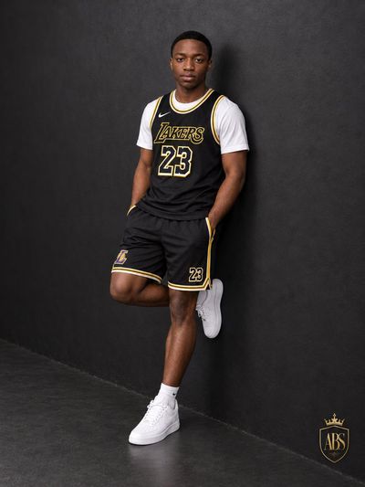 Confident Man Leans on Charcoal Wall in Lakers Jersey