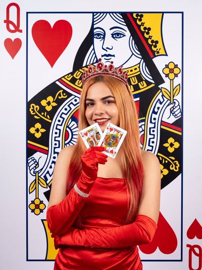 Smiling Woman in Ruby Crown Holds Winning Heart Cards