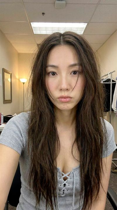 East Asian woman in dressing room with warm lamp glow