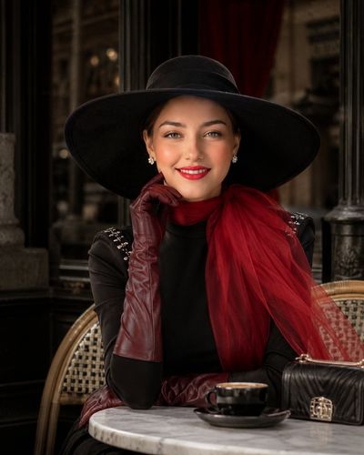 Elegant woman in black hat and red scarf poses confidently