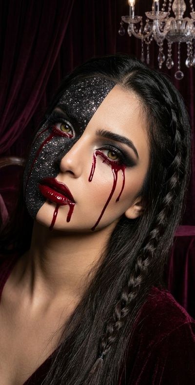 Gothic woman with split glitter and natural skin sheds blood tears