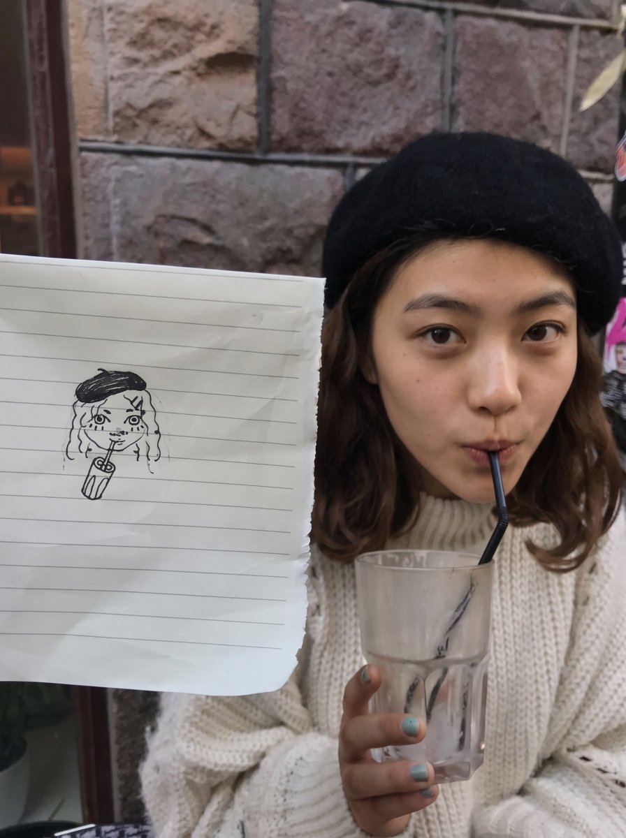 Woman in black beret sips iced drink at outdoor café