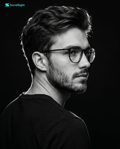 A young man with dark hair turns in a dramatic side profile