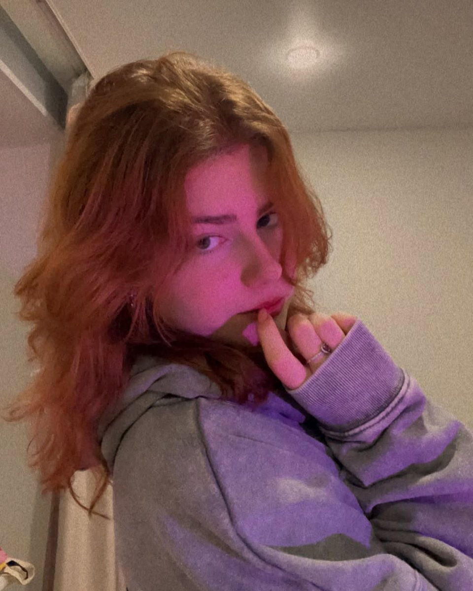 A woman rests her cheek on her hand in a blue car