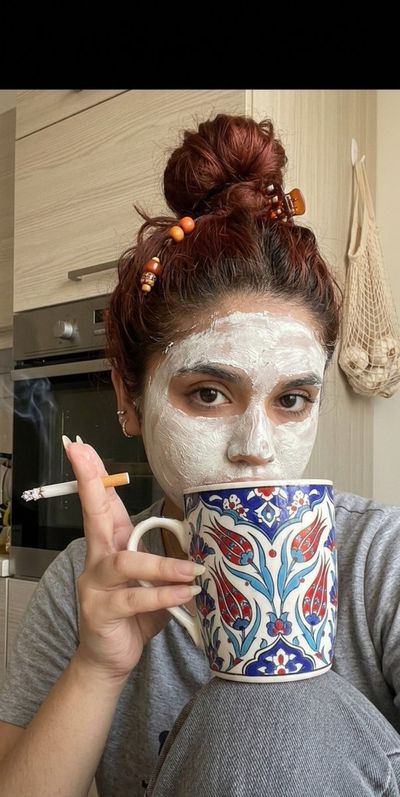 Woman with clay mask and Turkish mug enjoys a lazy morning