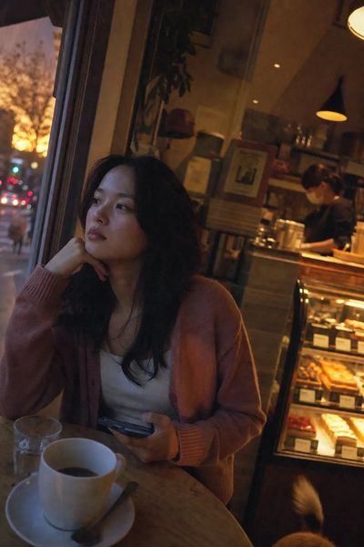Japanese woman sits pensively in warm amber cafe light