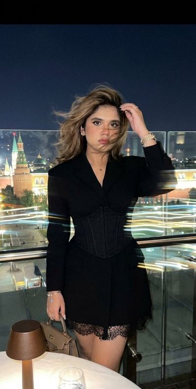 Woman Poses on Moscow Rooftop as City Lights Blur Behind Her