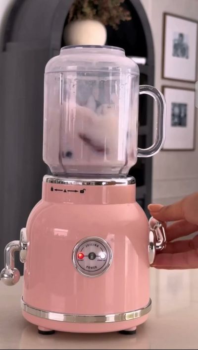 Hand Holds Chrome Handle on Vintage Pink Blender in Kitchen