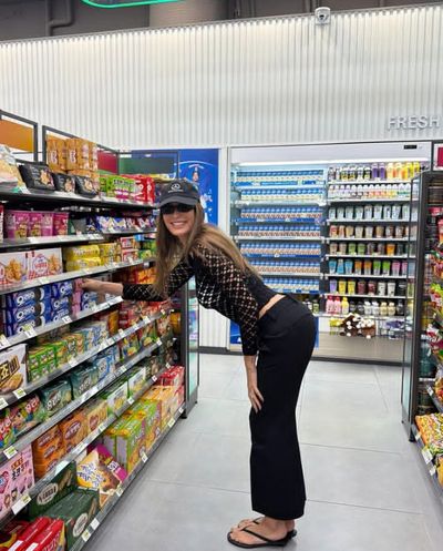 A young woman browses snacks in a cozy convenience store.