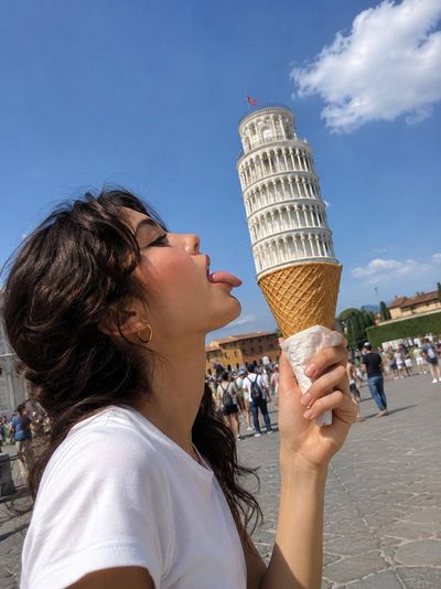 Woman licks cone with Leaning Tower of Pisa as scoop
