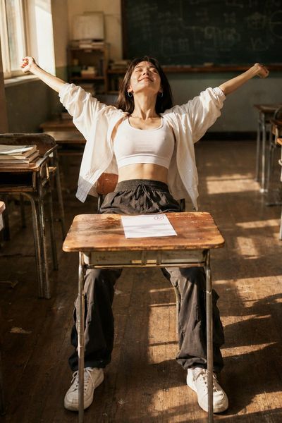 Korean woman stretches arms wide in golden classroom light