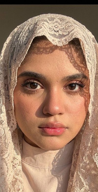 Woman behind lace veil smiles softly in warm sunlight